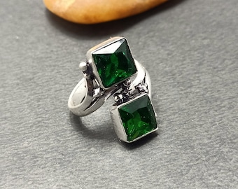 May include: A silver ring with two square green gemstones. The ring has a twisted band and is set with two square green gemstones.