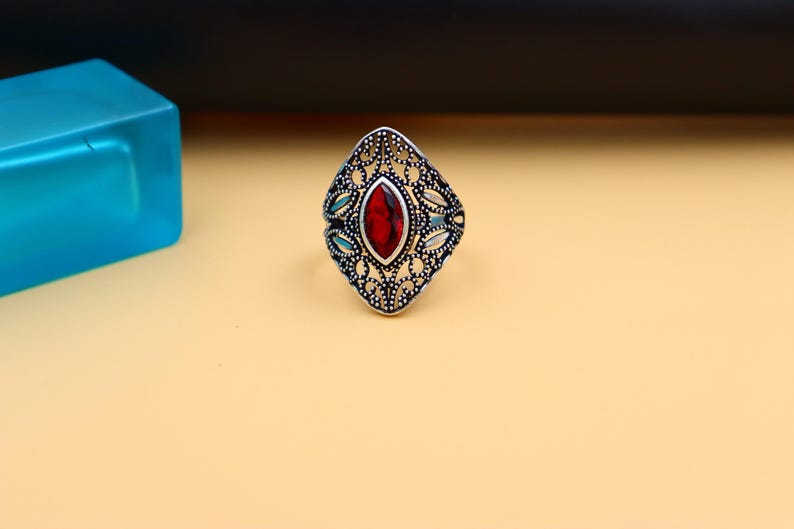 Op de afbeelding: Een zilveren ring met een rode edelsteen in een filigraan ontwerp.