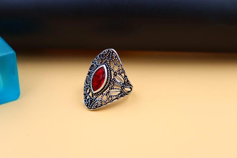 Op de afbeelding: Een zilveren ring met een rode edelsteen in een filigraan ontwerp.