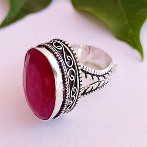 Peut inclure: Une bague en argent avec une pierre pr&eacute;cieuse ovale de couleur rose fonc&eacute; sertie dans un d&eacute;cor en argent orn&eacute; et d&eacute;taill&eacute;.