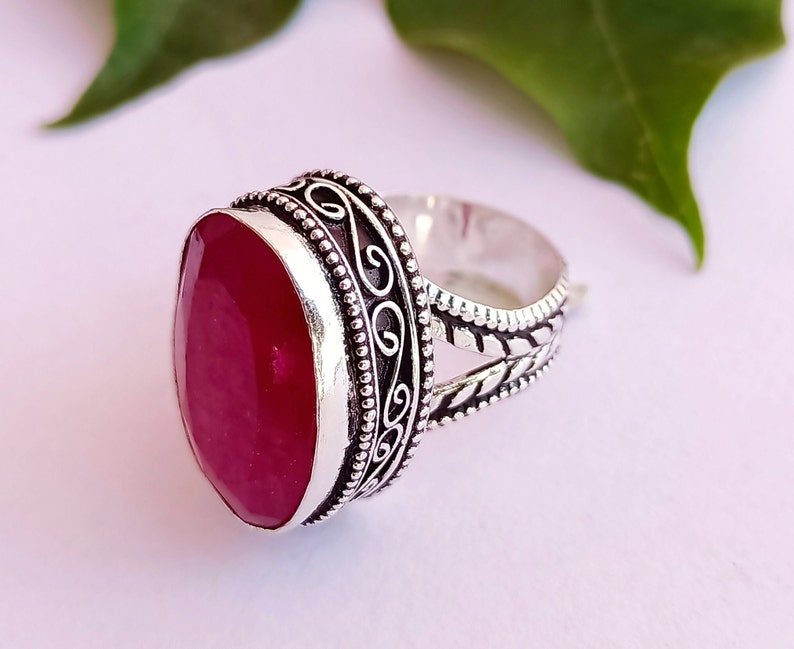 Peut inclure: Une bague en argent avec une pierre pr&eacute;cieuse ovale de couleur rose fonc&eacute; sertie dans un d&eacute;cor en argent orn&eacute; et d&eacute;taill&eacute;.