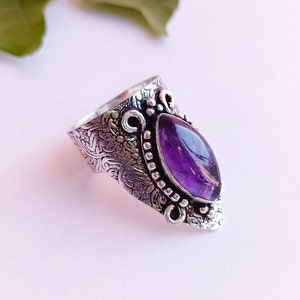 May include: A silver ring with an ornate design and a large, purple amethyst gemstone.