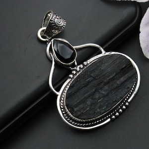 May include: Silver pendant featuring a black tourmaline gemstone with a black onyx accent. The pendant has a detailed silver design.