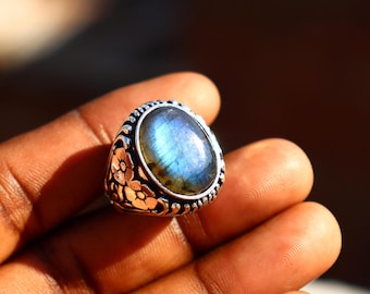 May include: A silver ring with a large oval-shaped blue labradorite gemstone set in a floral design.
