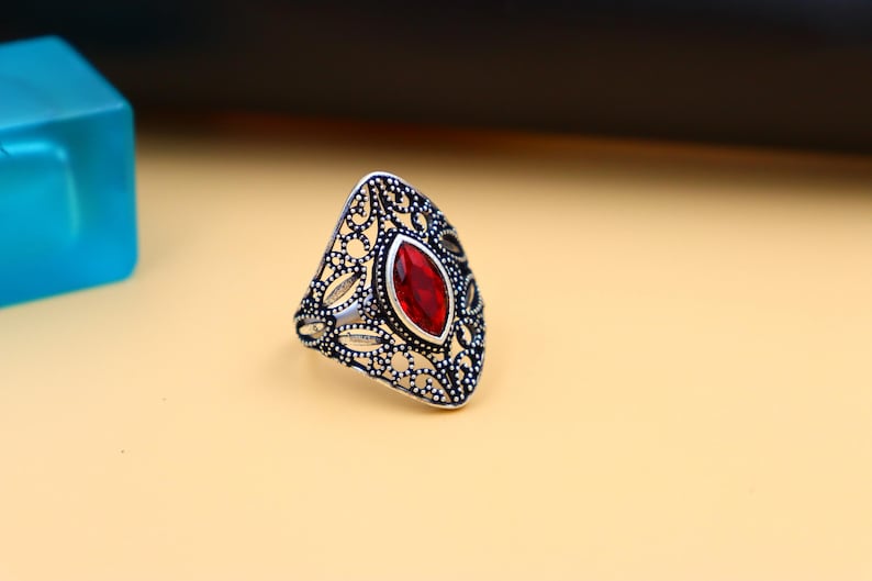 Op de afbeelding: Een zilveren ring met een rode edelsteen in een delicaat filigraan ontwerp.