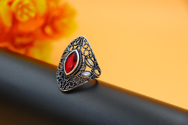 Op de afbeelding: Een zilveren ring met een rode edelsteen in een filigraan ontwerp.