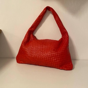 May include: A red woven leather handbag with a single strap.