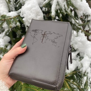 May include: A brown leather zippered Bible cover with a world map and a cross design.