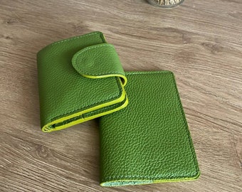 Puede incluir: Dos carteras de cuero verde con un acabado texturizado se muestran sobre una superficie de madera. Una cartera está cerrada con una solapa redondeada y un ribete amarillo. La otra cartera está abierta, revelando el interior. Las carteras son de color verde vibrante.