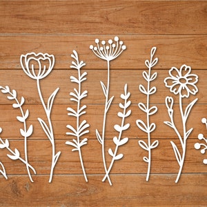 Könnte beinhalten: Ein Satz von neun weißen floralen Designs auf einem braunen Holzgrund. Die Designs beinhalten eine Vielzahl von Blumen, Blättern und Stielen.