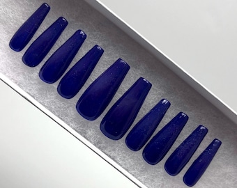 May include: A set of ten blue coffin-shaped press-on nails with a glittery finish.