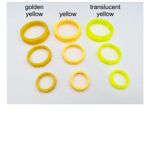 May include: A collection of yellow rings in varying shades: golden yellow, yellow, and translucent yellow. The rings are arranged in rows, with three different sizes of each color. The text labels each color.