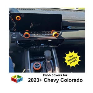 May include: Interior car detail with orange knob covers installed on a black dashboard. The image includes the text "knob covers for 2023+ Chevy Colorado". A yellow starburst graphic reads "Free Shipping in USA".