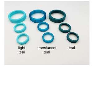 May include: An assortment of teal-colored rings in various sizes. The rings are labeled "light teal," "translucent teal," and "teal." The rings are arranged on a white surface.