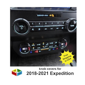 May include: Close-up of a black car dashboard with illuminated buttons and knobs. The dashboard features controls for volume, tuning, and climate. Text on the image reads "knob covers for 2018-2021 Expedition."