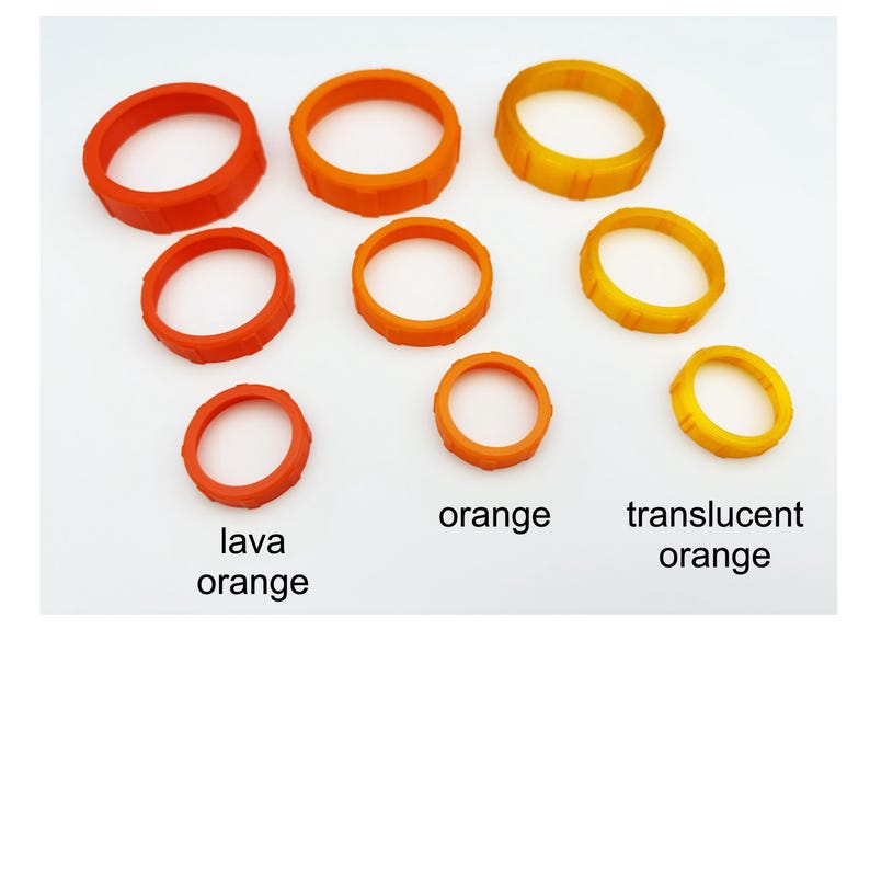 May include: An assortment of orange rings in varying sizes. The rings are labeled "lava orange", "orange", and "translucent orange". The rings are made of a plastic material and are arranged on a white surface.