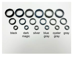 May include: A collection of rubber rings in various sizes and colors, including black, dark magic, silver, blue gray, oyster gray, and gray. The text labels each color. The rings are arranged in rows and columns.