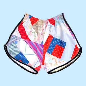 May include: Patchwork running shorts with a black trim. The shorts are made from a variety of fabrics in red, blue, pink, and white.
