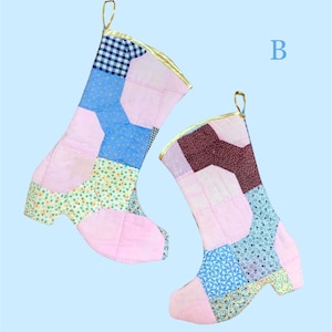 May include: Two patchwork Christmas stockings in the shape of boots. The stockings are made of various fabrics in pink, blue, and floral patterns. The tops are trimmed with gold fabric and have a gold loop for hanging.