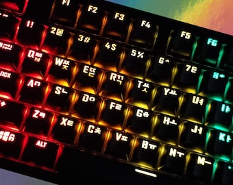 May include: A black keyboard with a rainbow-colored backlight. The keys are labeled with both English and Korean characters. The keyboard has a number pad and function keys.