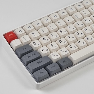May include: A white mechanical keyboard with gray keycaps. The keyboard has a standard layout with function keys, number keys, and letter keys. The keys are labeled with both English and Korean characters. The keyboard has a white frame and a white base.