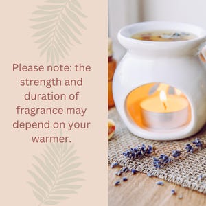 May include: A white ceramic essential oil warmer with a lit candle inside, surrounded by dried lavender and essential oil bottles. The text reads: "Please note: the strength and duration of fragrance may depend on your warmer."