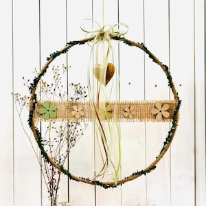 Könnte beinhalten: Ein grüner und brauner Kranz mit einem Juteband und Holzblumen. Der Kranz ist mit einem grünen Band und einem Holzhertz verziert.