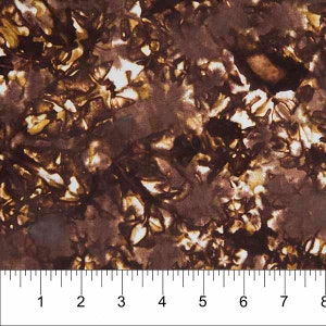 May include: Brown and white batik fabric with a floral pattern. The fabric is shown with a ruler for scale.