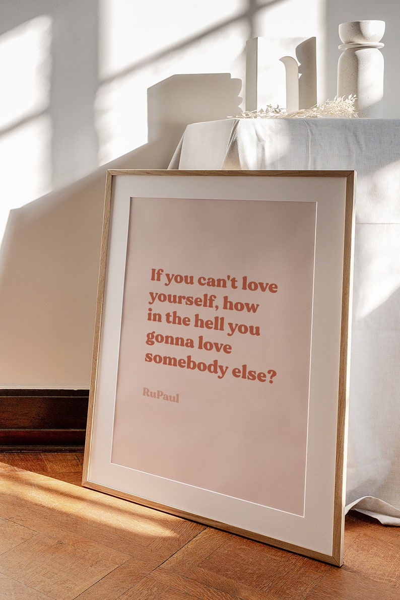 May include: A framed print with a pink background and a quote in bold red text: "If you can't love yourself, how in the hell you gonna love somebody else?"  The quote is attributed to RuPaul.