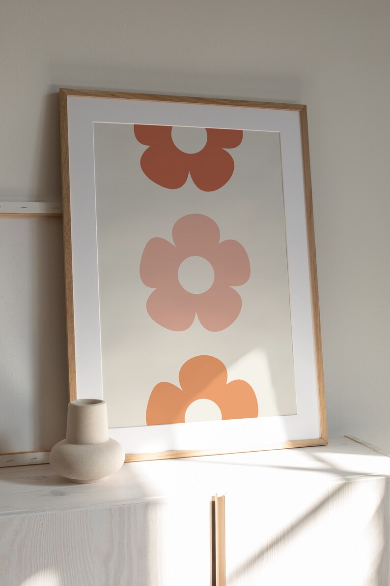 May include: A framed print with three stylized flowers in shades of orange and pink on a cream background.