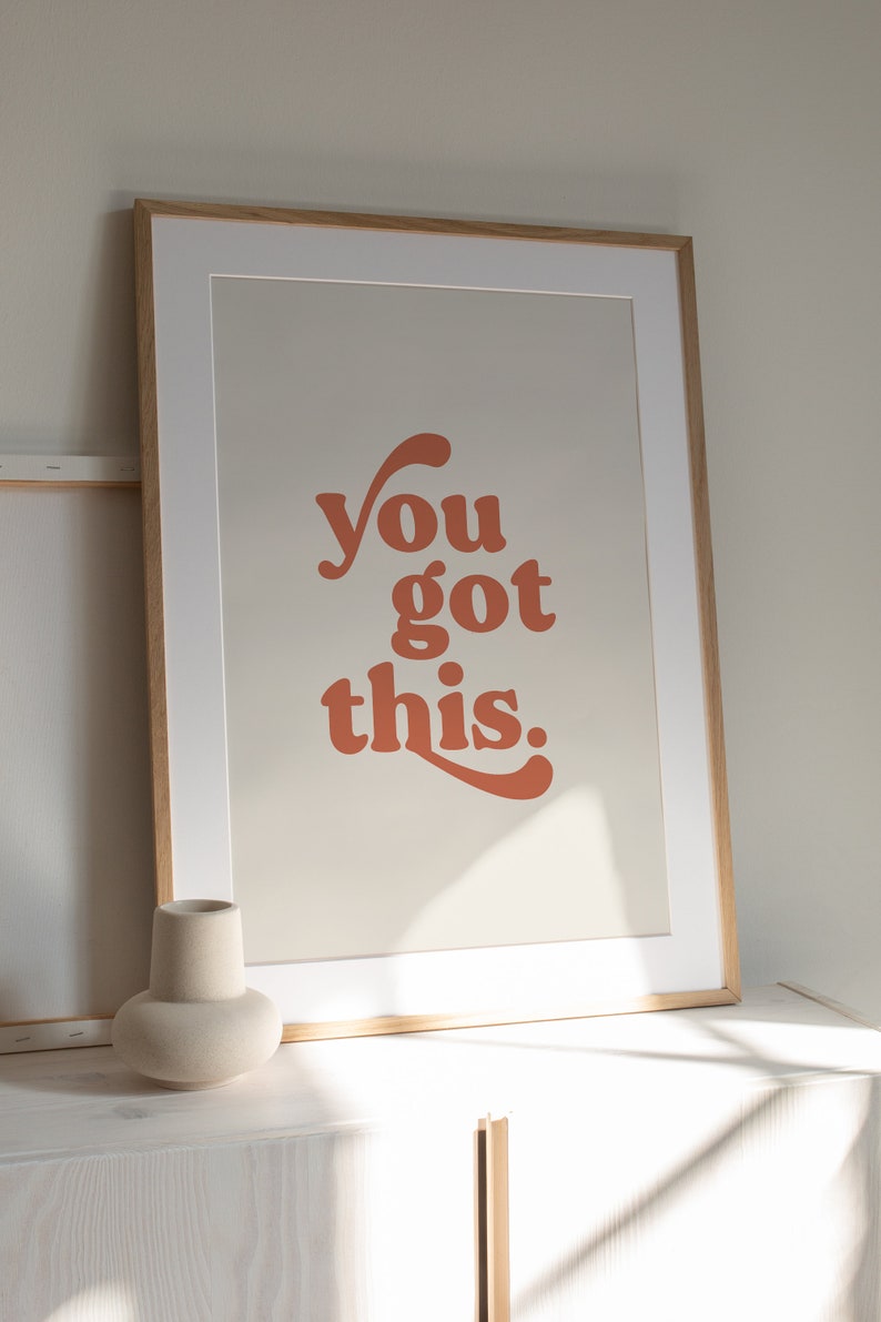 K&ouml;nnte beinhalten: Ein gerahmter Druck mit dem Text "you got this." in einer Retro-Orange-Schrift auf beigefarbenem Hintergrund.