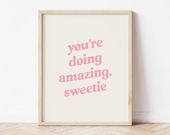 May include: A framed print with the text "you're doing amazing, sweetie" in pink lettering on a cream background.