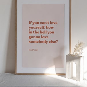 May include: A framed print with a pink background and a quote in brown text that reads "If you can't love yourself, how in the hell you gonna love somebody else?"  The quote is attributed to RuPaul.