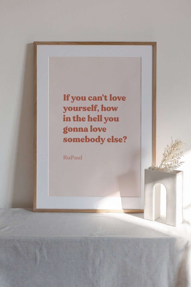 May include: A framed print with a pink background and a quote in brown text that reads "If you can't love yourself, how in the hell you gonna love somebody else?"  The quote is attributed to RuPaul.