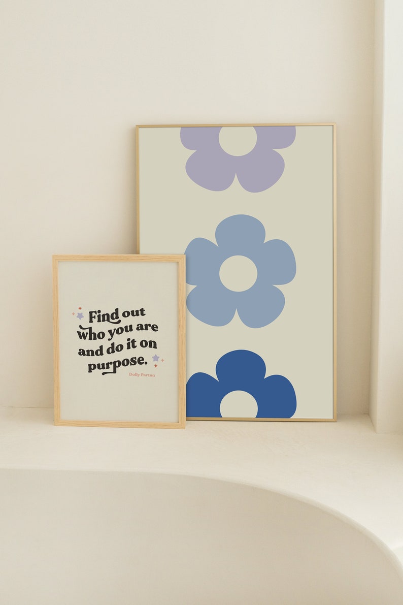 K&ouml;nnte beinhalten: Zwei gerahmte Drucke mit einem motivierenden Zitat und einem Muster aus blauen und violetten Blumen. Das Zitat lautet "Finde heraus, wer du bist, und tue es mit Absicht." Das Zitat wird Dolly Parton zugeschrieben.