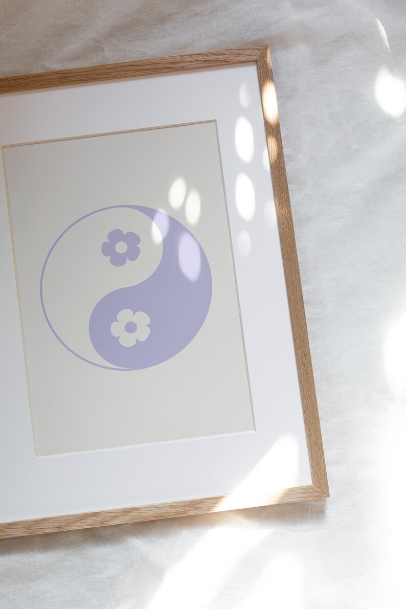 Może przedstawiać: Wydruk w ramie przedstawiający fioletowy symbol yin yang z białymi kwiatami wewnątrz każdej połowy symbolu. Wydruk jest na kremowym tle i jest oprawiony w jasną drewnianą ramę.