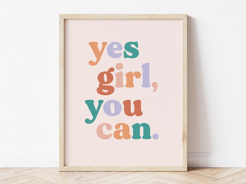 May include: A framed print with a pink background and the text "yes girl, you can." in colorful, stylized lettering.