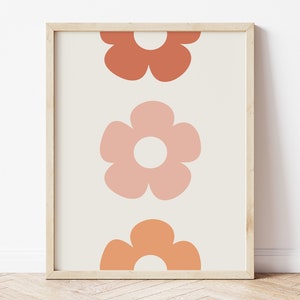 May include: A framed print with a minimalist design featuring three stylized flowers in shades of orange and pink on a cream background.
