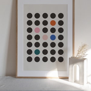 Puede incluir: Una impresi&oacute;n enmarcada con un dise&ntilde;o minimalista que presenta una cuadr&iacute;cula de c&iacute;rculos negros con algunos c&iacute;rculos de colores en el centro. Los c&iacute;rculos de colores son naranja, rosa, azul y turquesa.