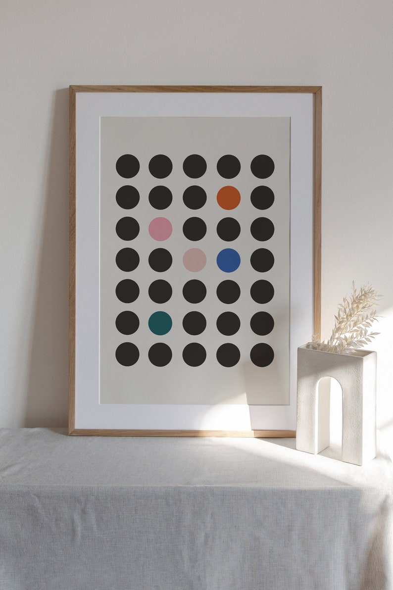 Puede incluir: Una impresi&oacute;n enmarcada con un dise&ntilde;o minimalista que presenta una cuadr&iacute;cula de c&iacute;rculos negros con algunos c&iacute;rculos de colores en el centro. Los c&iacute;rculos de colores son naranja, rosa, azul y turquesa.