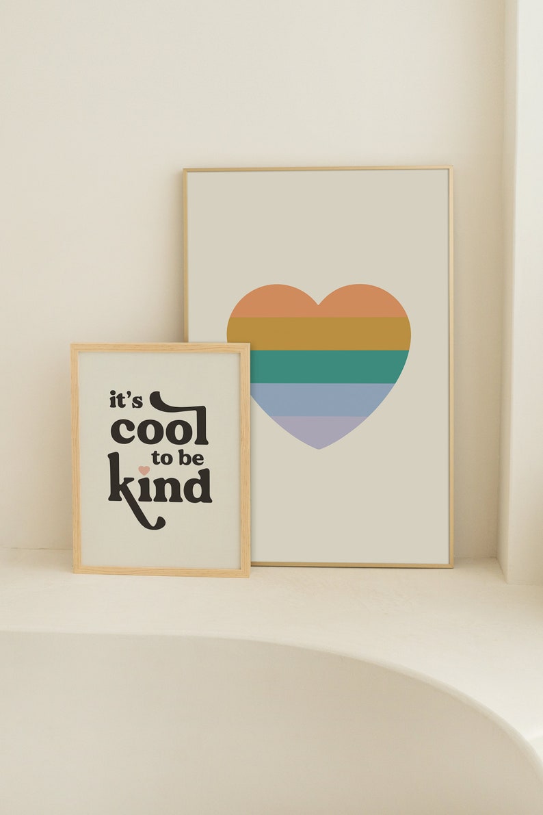 May include: Two framed prints with a minimalist design. The print on the left features the text "it's cool to be kind" in black with a small pink heart. The print on the right features a multi-colored heart with orange, yellow, green, and purple stripes.