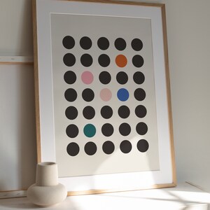 Puede incluir: Una impresi&oacute;n enmarcada con un dise&ntilde;o minimalista que presenta una cuadr&iacute;cula de c&iacute;rculos negros con toques de color, incluyendo naranja, rosa, azul y turquesa.