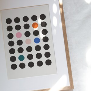 Puede incluir: Una impresi&oacute;n enmarcada con fondo blanco y una cuadr&iacute;cula de c&iacute;rculos negros. Hay cinco c&iacute;rculos de colores en la cuadr&iacute;cula: naranja, rosa, azul y verde azulado.