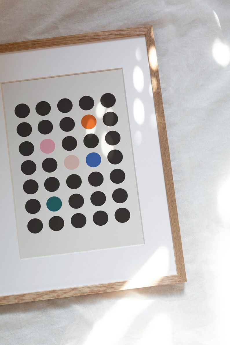Puede incluir: Una impresi&oacute;n enmarcada con fondo blanco y una cuadr&iacute;cula de c&iacute;rculos negros. Hay cinco c&iacute;rculos de colores en la cuadr&iacute;cula: naranja, rosa, azul y verde azulado.