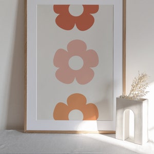 May include: A framed print with three stylized flowers in shades of orange, pink, and red on a beige background.