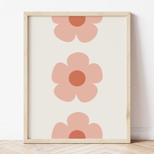 K&ouml;nnte beinhalten: Gerahmter Kunstdruck mit einem sich wiederholenden Muster aus drei gro&szlig;en, stilisierten Blumen. Die Blumen sind in einem sanften Pfirsichton mit dunkleren Pfirsichzentren auf cremefarbenem Hintergrund gehalten. Der Rahmen ist hellholzfarben.