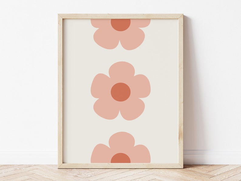 K&ouml;nnte beinhalten: Gerahmter Kunstdruck mit einem sich wiederholenden Muster aus drei gro&szlig;en, stilisierten Blumen. Die Blumen sind in einem sanften Pfirsichton mit dunkleren Pfirsichzentren auf cremefarbenem Hintergrund gehalten. Der Rahmen ist hellholzfarben.