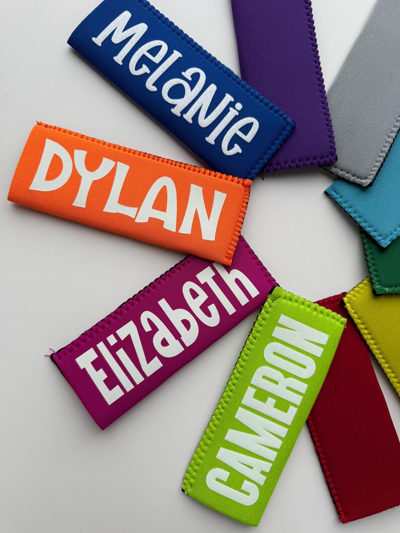 May include: A collection of rectangular neoprene beverage sleeves in various colors including orange, blue, purple, gray, light blue, green, yellow, red, and lime green. Several sleeves feature white printed names: Melanie, Dylan, Elizabeth, and Cameron.