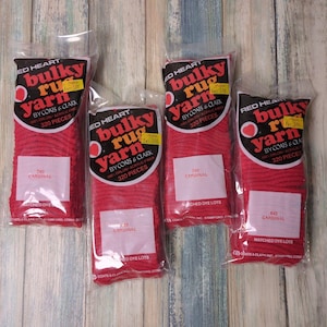 May include: Four packages of Red Heart Bulky Rug Yarn in Cardinal red. Each package contains 320 pieces of 100% Orlon acrylic fiber. The packages are sealed in clear plastic.