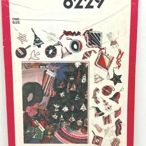 May include: A Simplicity 8229 sewing pattern envelope featuring illustrations of various fabric Christmas ornaments, including stars, bells, and balls, alongside a photograph of a decorated Christmas tree with a tree skirt and stocking.